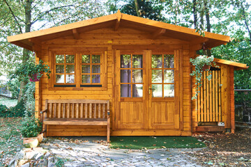 Beautiful wood cabin with gazebo, surrounded by trees and plants.