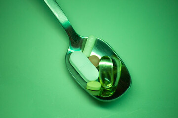 close up of different and pills tablets in the spoon in green light