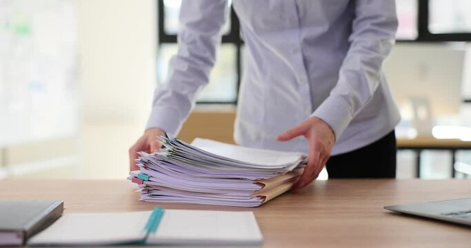 Businesswoman manager or secretary takes away stack of documents from desktop