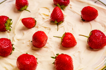 Fresh juicy red strawberries with green sprigs in thick whipped cream close-up