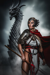 Fototapeta na wymiar A fierce warrior woman stands with a spear before a menacing dragon, exuding confidence and strength against a stormy backdrop