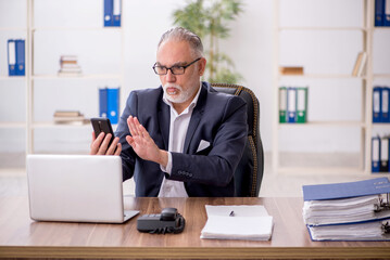 Naklejka premium Old male employee working in the office