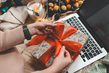 Girl with a gift box in her hands near the Christmas tree, isolated screen on a laptop