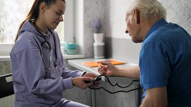 A nurse tries to check the blood pressure on a special device called a blood pressure monitor in an elderly man
