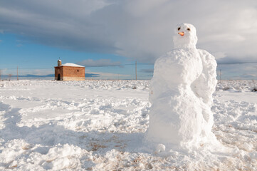 Paisaje invernal con un muñeco de nieve en el campo nevado durante las Navidades.