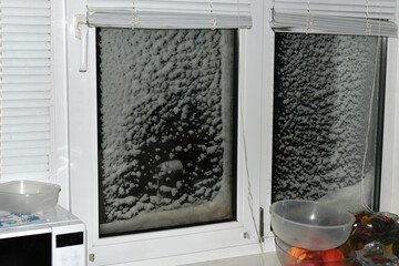 A plastic window frame, the window blocks of which were covered with wet, thick snow by a strong...