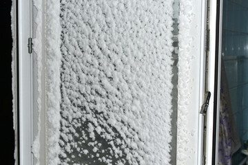 View of window glass, from the side of the streets, covered with thick, cold snow.