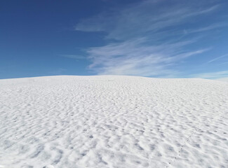 Fototapeta na wymiar fluffy white freshly fallen snow on hill in mountains contrasting with clear blue sky in winter