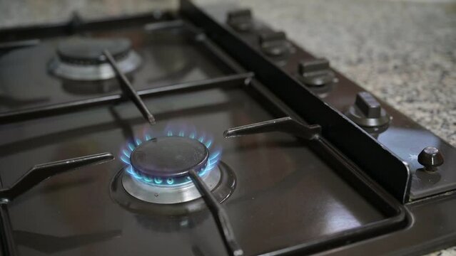 A male hand raises the kitchen gas burner and then turns off the kitchen gas burner.
