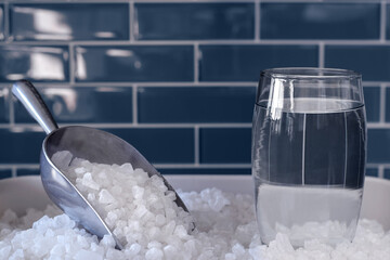 Glass of water and water softener salt for hard water treatment concept