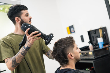 hairdresser drying client's hair after cutting his hair