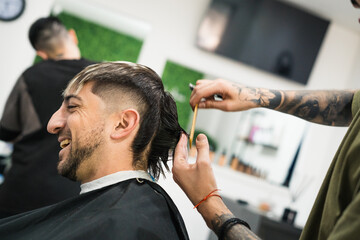 barber cutting hair with scissors for happy customer