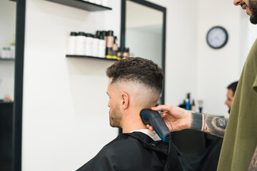 barber cutting customer's hair with machine