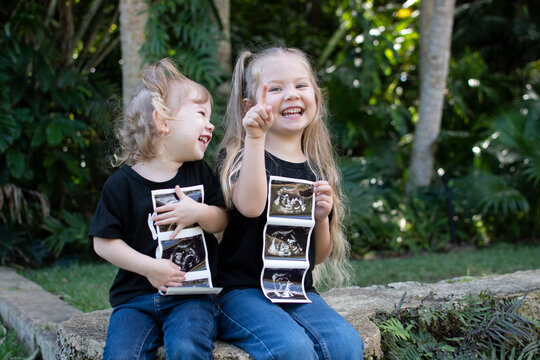Pregnancy announcement by siblings. Social media pregnancy announcement. Big sister. The third child in a family. Two kids holding a sonogram of a new baby 
