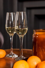 Two glasses of champagne and tangerines on a table against blurred black background. New year celebration party.Winter holidays celebration
