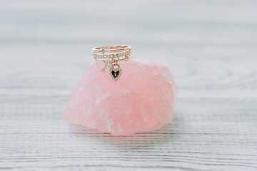 A gold ring with a heart on rose quartz on a light background