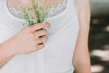 A gold ring on a woman's hand holding white flowers