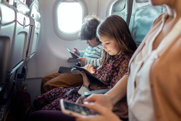 Little boy and girl sitting on airplane using tablet