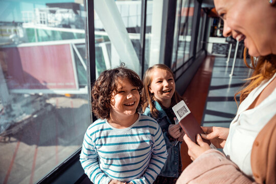 Joyful Children and Mother Receiving Boarding Passes for Their Flight