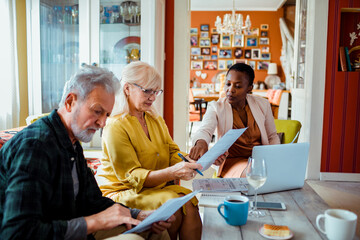 Senior couple going over documents with financial advisor at home