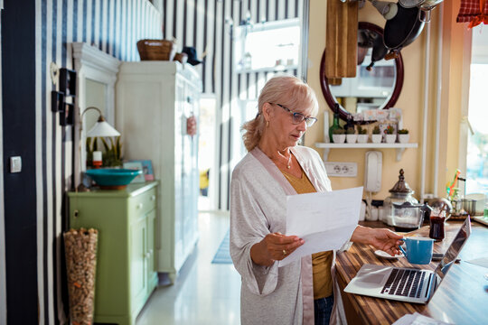 Senior woman standing holding document at home
