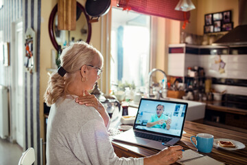 Mature senior woman talking to doctor on video call from home