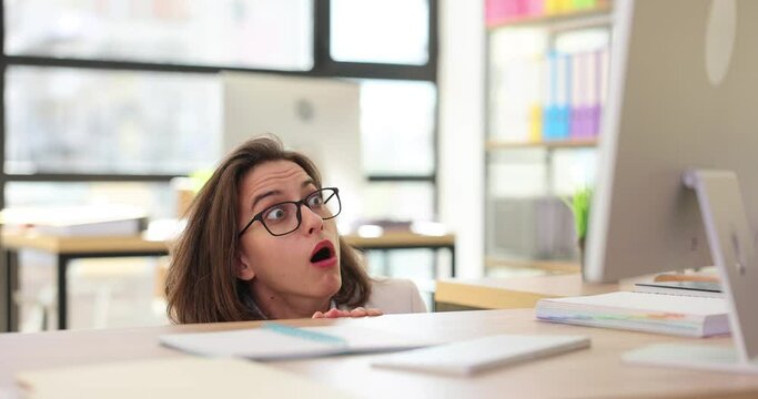 Frightened and shocked woman in panic at table looking at computer screen