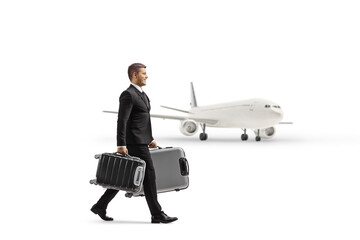 Full length profile shot of a businessman in a suit walking and carrying suitcases