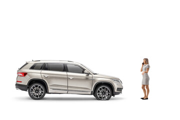 Full length profile shot of a young woman using a smartphone in front of a SUV