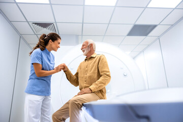 Nurse holding patient hand and encouraging him for MRI scanning test in hospital.