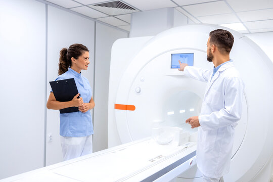 Team of radiologists and doctors checking and preparing modern MRI scanning machine in hospital.