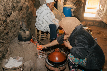Couple cooking and lighting firewood with kettle in local kitchen