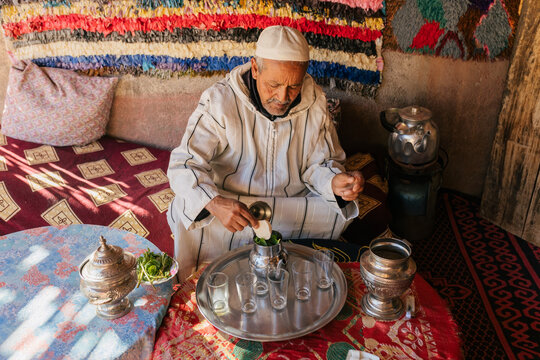 Man in traditional clothes preparing Moroccan tea in cup