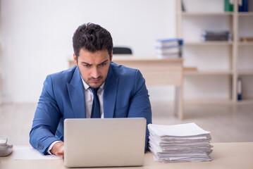 Young male employee and too much work in the office