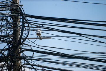 An electrical pole that shows the disorder in the arrangement of the cables.
