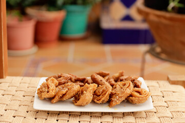 Moroccan chebakias on a white plate in a patio with plants