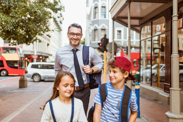Happy father walking kids to school after work