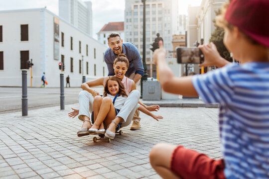 Family playing on skateboard in city taking picture