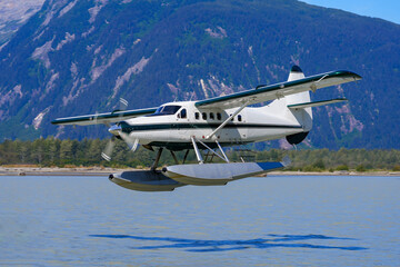Fototapeta na wymiar Seaplane taking off from a melt water lake in the Alaskan mountains north of Juneau in the Taku inlet