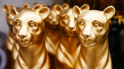 Close-up of many golden decorative figurines of panthers - obrazy, fototapety, plakaty