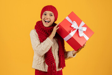 European lady in knit hat with Christmas gift box, studio