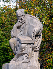 Fototapeta na wymiar Statue of Aristophanes with an open book at the Lazienki park amphitheater in Warsaw, Poland