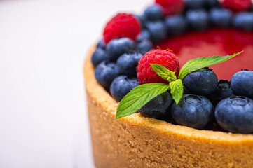 top view, close-up of cheese cheesecake decorated with fresh berries, blueberries and raspberries on light background, place for text