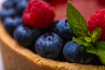 close-up of cheesecake decorated with fresh berries, blueberries and raspberries and mint leaves. confectionery, baking, bright colors