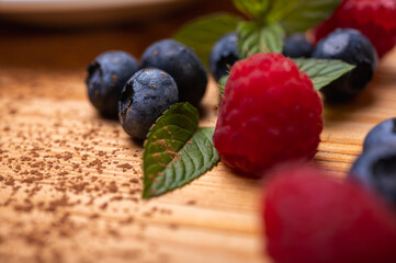 fresh blueberries and raspberries and mint leaves decorated cheesecake close-up. Confectionery, baking, bright colors	
