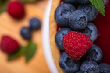 close-up of cheesecake decorated with fresh berries, blueberries and raspberries and mint leaves. confectionery, baking, bright colors