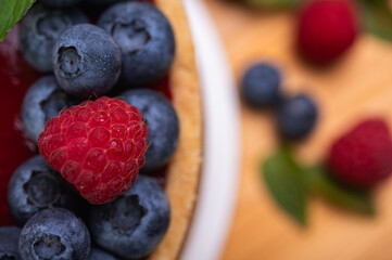 close-up of cheesecake decorated with fresh berries, blueberries and raspberries and mint leaves. confectionery, baking, bright colors