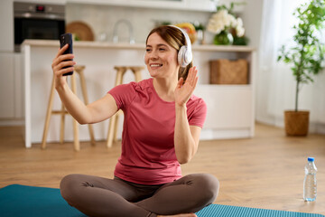 Fototapeta na wymiar Young woman using cellphone and taking Selfie while exercising yoga at home