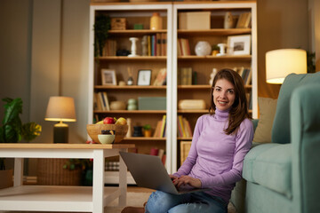 Young smiling woman working remotely from home on laptop