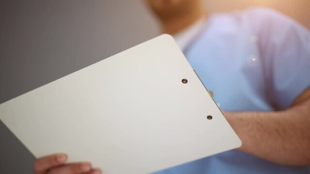 Portrait of a senior doctor holding notes against a gray background. close-up